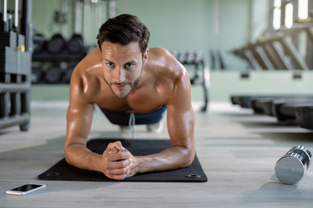 Male athlete in plank pose exercising at health club.